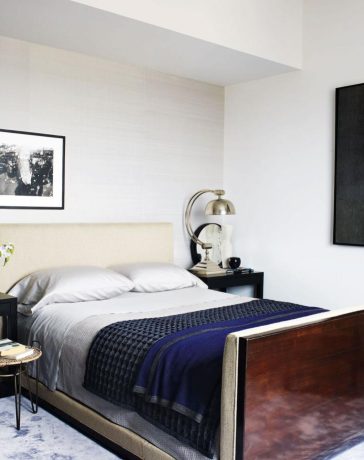 a wall of the master bedroom is covered in a silk by mdc wallcoverings and the bed bedding bedside tables and rug are by calvin klein home the side table and lamps are vintage and the painting is by carlos vega