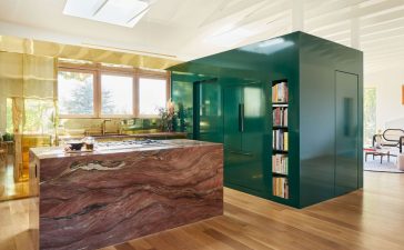 green lacquered cube hold appliances next to an island in pink marble