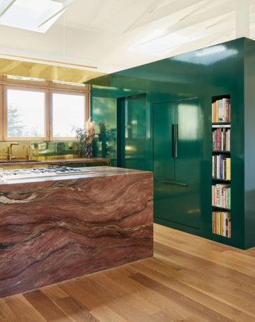 green lacquered cube hold appliances next to an island in pink marble