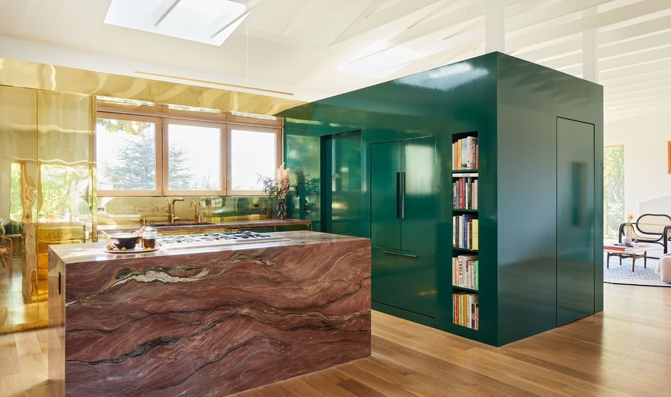 green lacquered cube hold appliances next to an island in pink marble