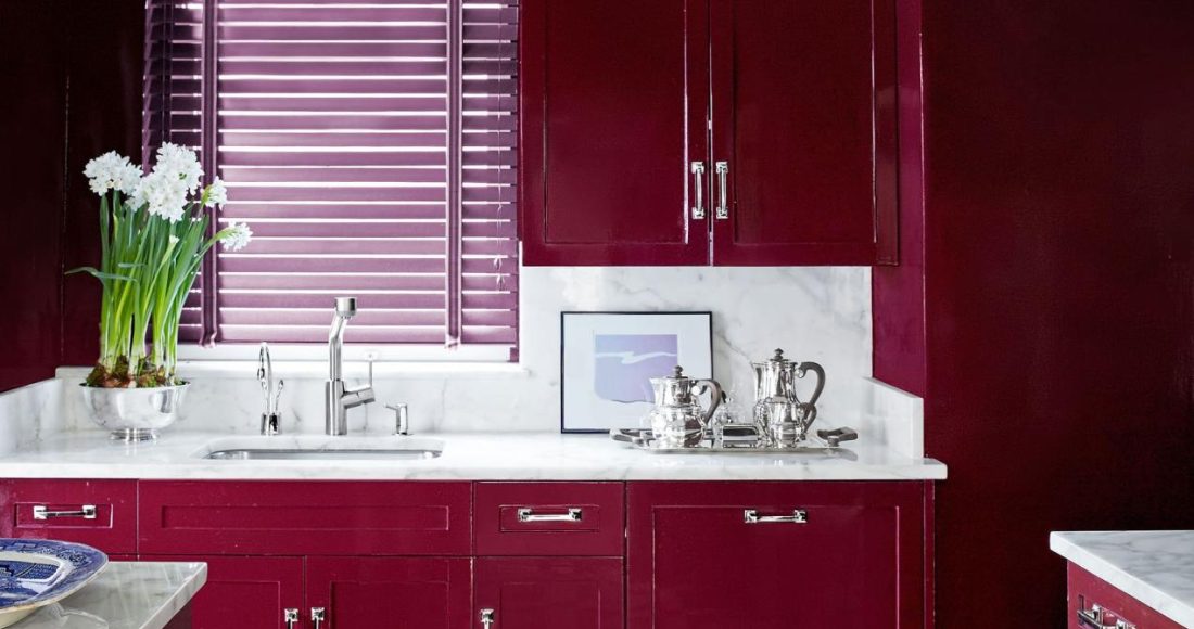 kitchen with red cherry cabinets and white marble counters and black and white geometric floor