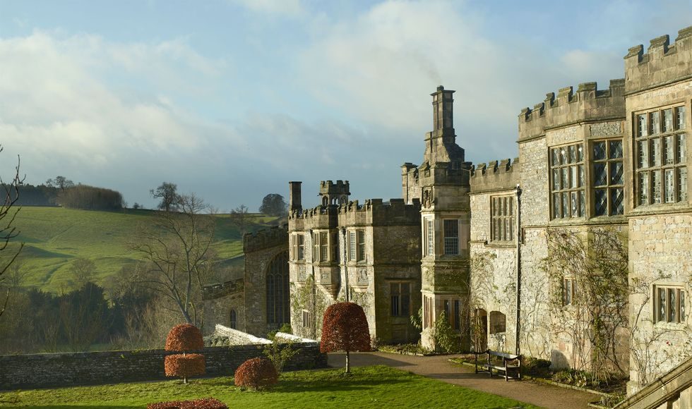 a large english manor building made of stone with a extensive lawn in front of it